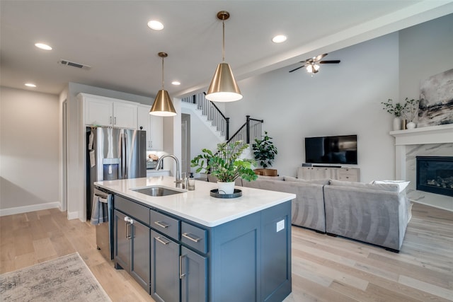 kitchen with white cabinets, a sink, stainless steel appliances, open floor plan, and visible vents