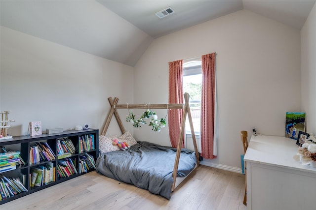 bedroom featuring baseboards, vaulted ceiling, light wood finished floors, and visible vents
