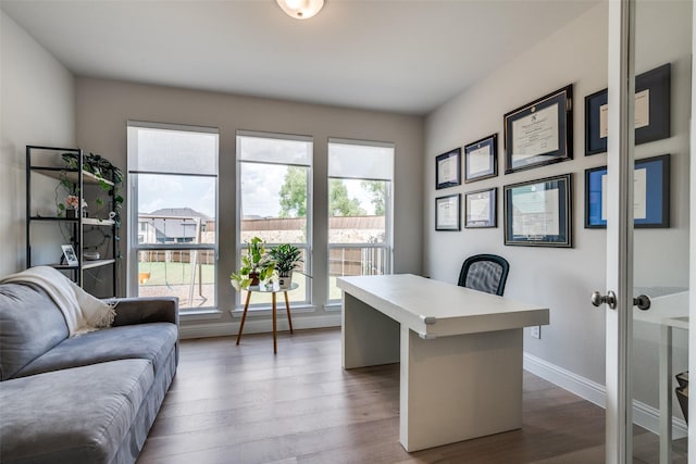 office space featuring baseboards, wood finished floors, and a healthy amount of sunlight