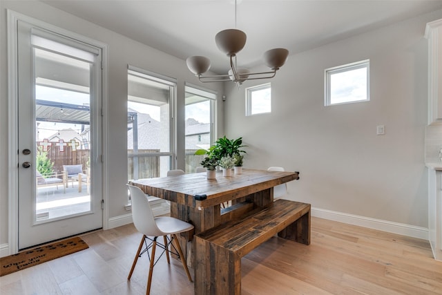 dining room with baseboards, a chandelier, and light wood-style flooring