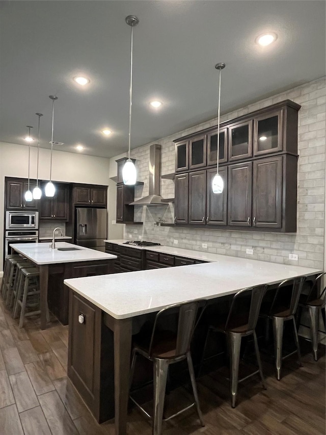 7040 Cross Point Ln, Little Elm, TX 76227 - kitchen featuring wall chimney range hood, appliances with stainless steel finishes, a sink, a kitchen breakfast bar, and tasteful backsplash