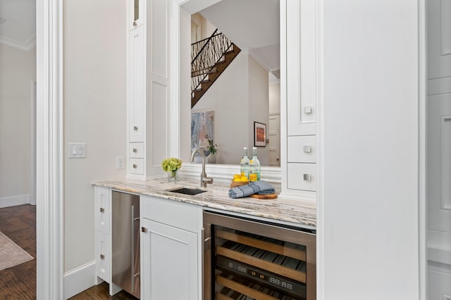 bar featuring beverage cooler, baseboards, a sink, stairs, and crown molding