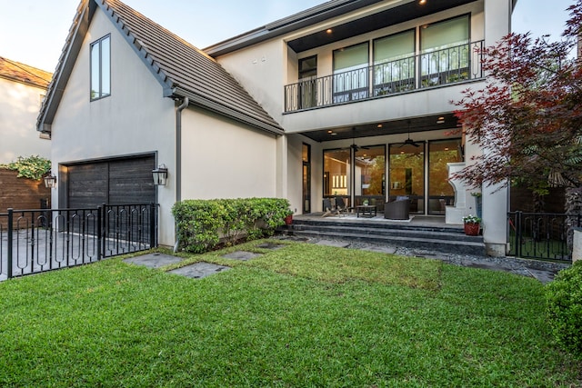 back of house featuring a lawn, fence, stucco siding, and a balcony