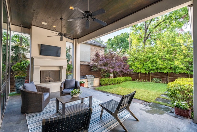 view of patio with an outdoor fireplace, fence, a grill, a ceiling fan, and an outdoor kitchen