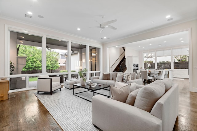 living area featuring a ceiling fan, crown molding, plenty of natural light, visible vents, and stairs