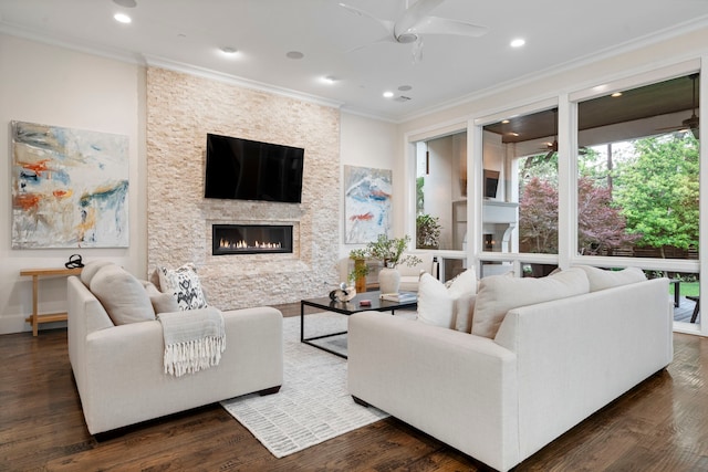 living room featuring wood finished floors, recessed lighting, crown molding, a ceiling fan, and a stone fireplace