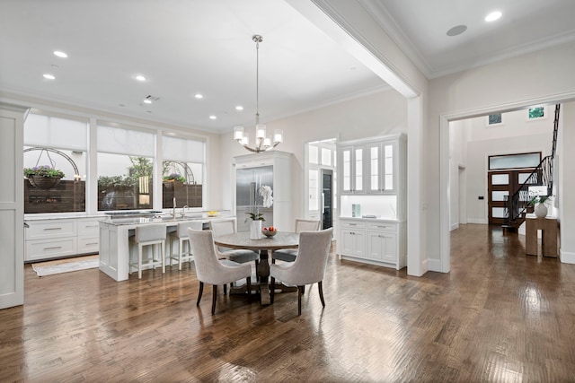 dining space with a chandelier, wood finished floors, ornamental molding, and recessed lighting
