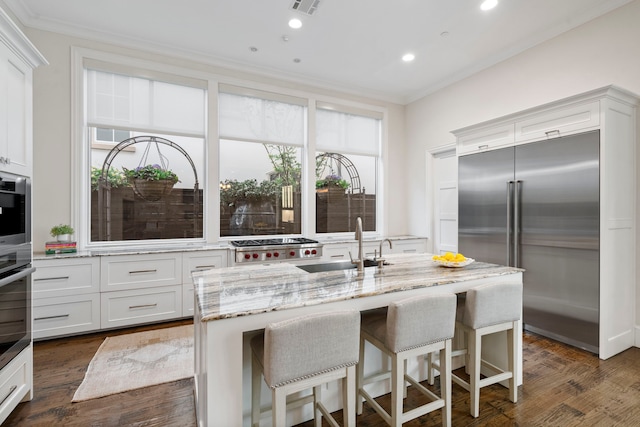 kitchen featuring a sink, crown molding, stainless steel appliances, and light stone counters