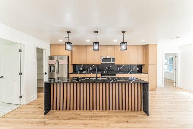 229 W Oaks Cir, Sulphur Springs, TX 75482 - kitchen with stainless steel appliances, an island with sink, light wood-type flooring, tasteful backsplash, and baseboards