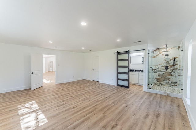 229 W Oaks Cir, Sulphur Springs, TX 75482 - empty room with a barn door, light wood-style flooring, recessed lighting, and baseboards