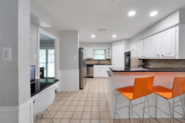 2227 Timberwood, Carrollton, TX 75006 - kitchen with a sink, a peninsula, stainless steel appliances, white cabinetry, and dark countertops