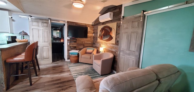living area featuring lofted ceiling, wood walls, wood finished floors, a barn door, and a wall unit AC