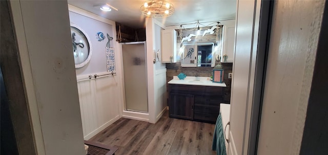 full bathroom featuring a stall shower, vanity, a wainscoted wall, and wood finished floors
