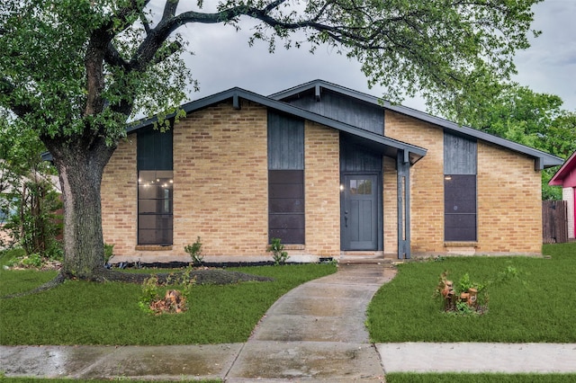 mid-century modern home with brick siding and a front yard