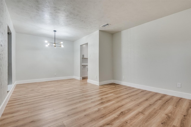interior space with baseboards, light wood-style floors, a chandelier, and visible vents
