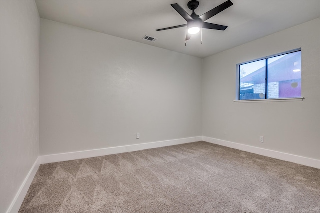 carpeted spare room featuring baseboards, ceiling fan, and visible vents