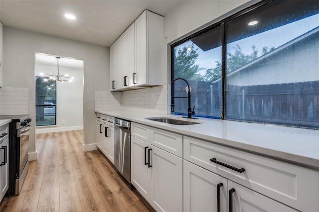 kitchen with light wood-style floors, stainless steel appliances, light countertops, and a sink