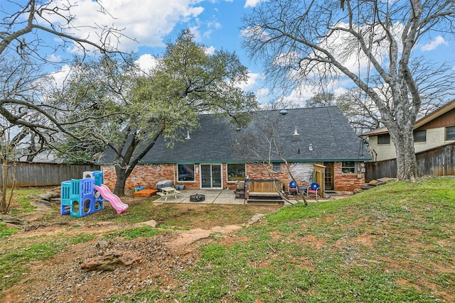 back of house featuring a lawn, brick siding, a patio, a shingled roof, and a fenced backyard