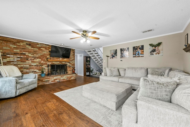 living area with ornamental molding, ceiling fan, visible vents, wood finished floors, and stairway