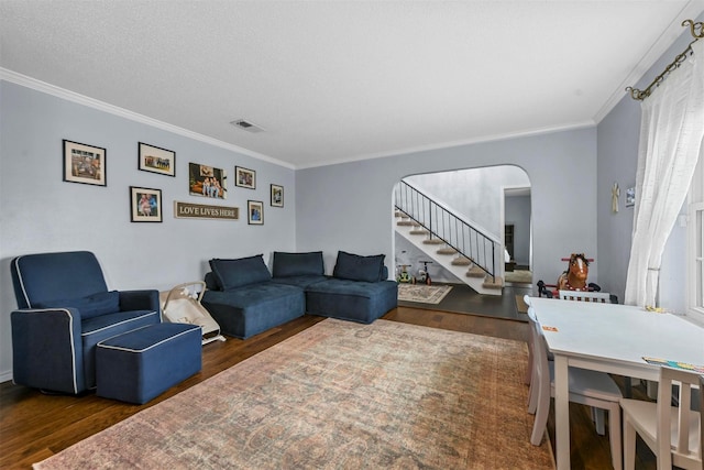 living area featuring crown molding, stairs, visible vents, and wood finished floors