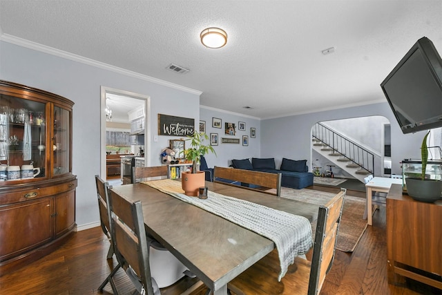 dining space featuring a textured ceiling, ornamental molding, visible vents, dark wood-type flooring, and stairway