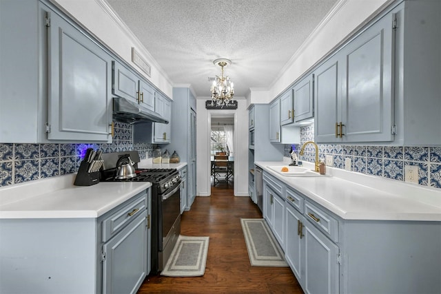 kitchen featuring a sink, under cabinet range hood, backsplash, a notable chandelier, and appliances with stainless steel finishes