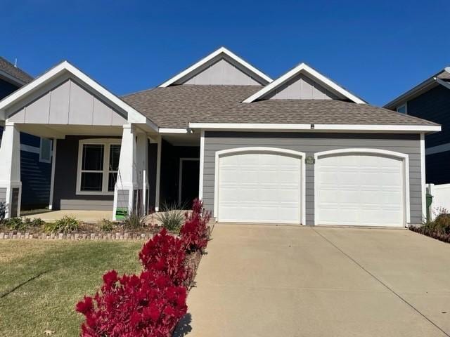 view of front of property with a front yard, an attached garage, a shingled roof, and driveway