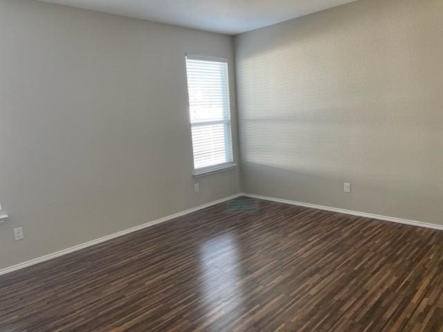empty room featuring baseboards and dark wood-style floors