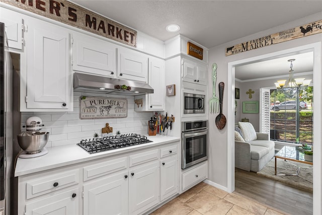 1105 Charles St, Weatherford, TX 76086 - kitchen featuring appliances with stainless steel finishes, under cabinet range hood, a chandelier, light countertops, and crown molding