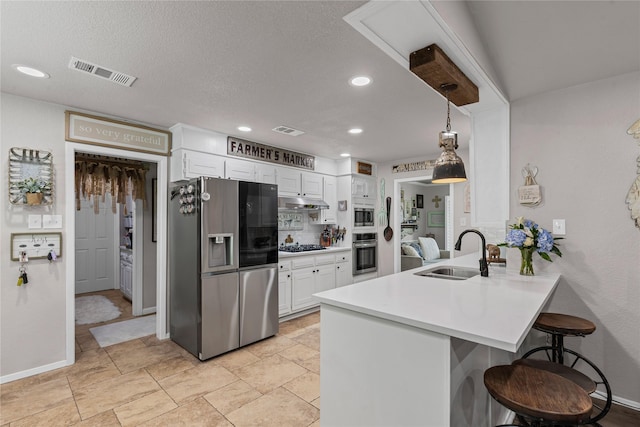 1105 Charles St, Weatherford, TX 76086 - kitchen with appliances with stainless steel finishes, a sink, a breakfast bar, a peninsula, and white cabinets