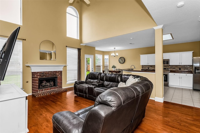 living area with a brick fireplace, a ceiling fan, and wood finished floors
