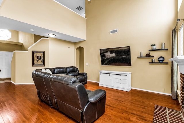 living area featuring visible vents, wood finished floors, and a brick fireplace