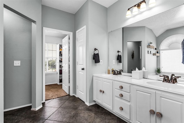 bathroom with tile patterned floors, double vanity, baseboards, and a sink