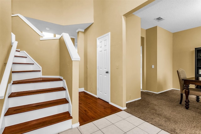 staircase with tile patterned flooring, carpet flooring, baseboards, and visible vents