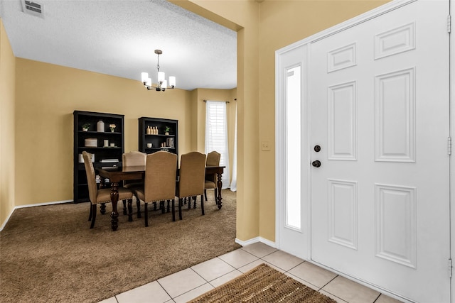 entrance foyer featuring baseboards, light tile patterned flooring, visible vents, a chandelier, and light colored carpet