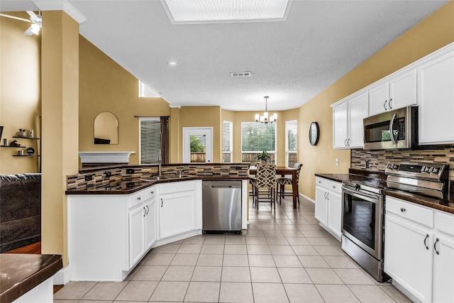 kitchen with dark countertops, stainless steel appliances, visible vents, and decorative backsplash