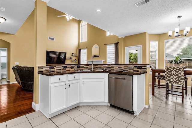 kitchen with stainless steel dishwasher, open floor plan, dark countertops, and visible vents