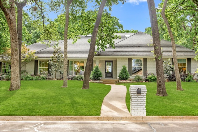 single story home with brick siding, a tile roof, and a front yard