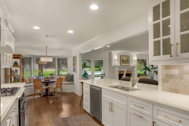 kitchen featuring a warm lit fireplace, light countertops, appliances with stainless steel finishes, and a sink