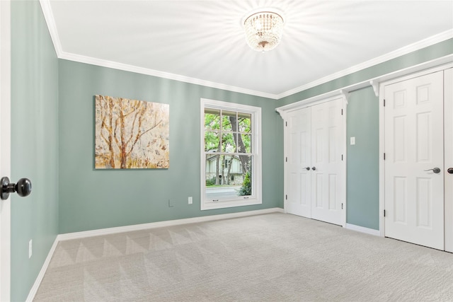 unfurnished bedroom featuring carpet flooring, an inviting chandelier, baseboards, and crown molding