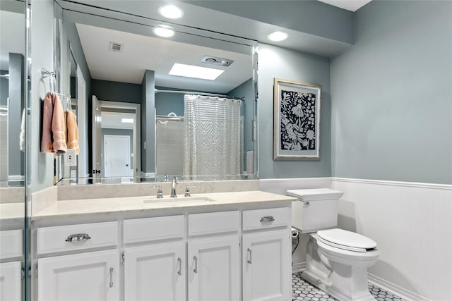 bathroom featuring toilet, a wainscoted wall, visible vents, tile patterned flooring, and vanity