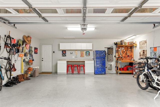 garage featuring a workshop area, freestanding refrigerator, and a garage door opener