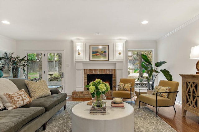 living area with crown molding, a brick fireplace, baseboards, and wood finished floors
