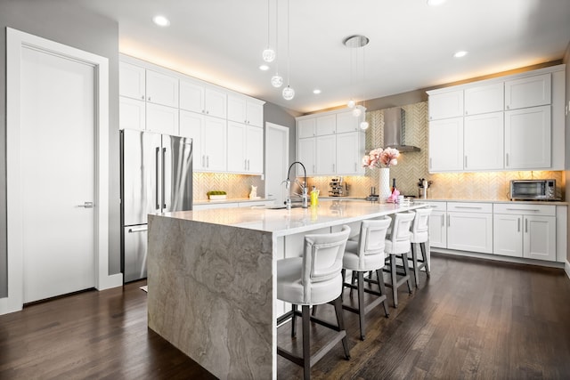 kitchen featuring freestanding refrigerator, a sink, wall chimney exhaust hood, dark wood-style floors, and recessed lighting