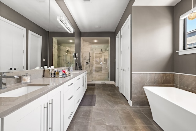 bathroom featuring a stall shower, double vanity, a freestanding tub, and marble finish floors