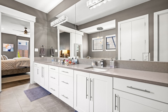 ensuite bathroom with double vanity, a ceiling fan, plenty of natural light, and a chandelier