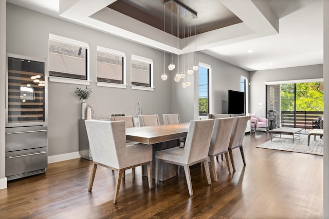 dining room featuring a tray ceiling, dark wood-style floors, beverage cooler, recessed lighting, and baseboards