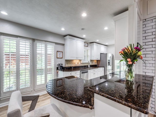17607 Seedling Ct, Dallas, TX 75287 - kitchen featuring appliances with stainless steel finishes, light wood-style flooring, decorative backsplash, white cabinetry, and recessed lighting