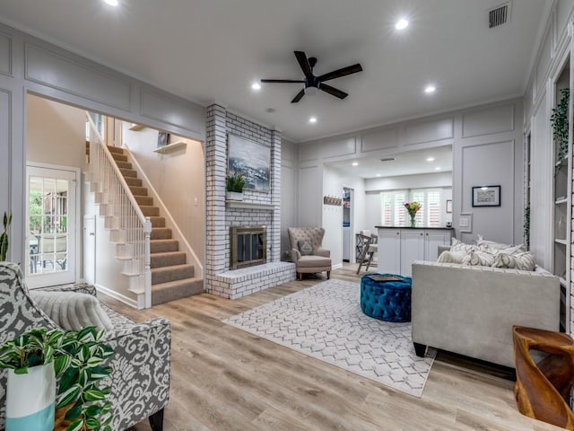17607 Seedling Ct, Dallas, TX 75287 - living room featuring a ceiling fan, wood finished floors, a decorative wall, a fireplace, and stairs