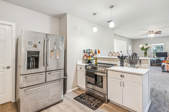 kitchen with a peninsula, stainless steel appliances, open floor plan, light countertops, and a ceiling fan